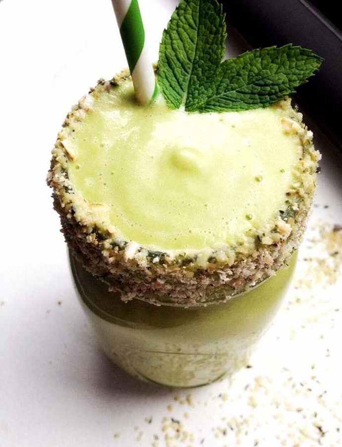 a lime green colored mint smoothie in a mason jar with a hemp seed crusted rim and mint leaves